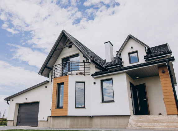 Modern two-story house with a garage, featuring a sloped roof, large windows, and a balcony