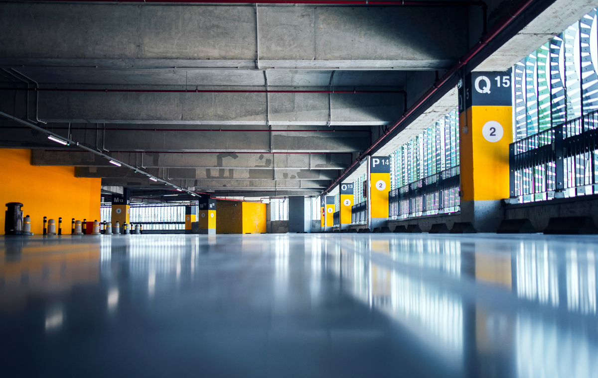 A modern, empty parking garage with yellow and gray pillars, marked with alphanumeric codes for parking spaces